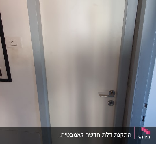 דלת לבנה עם מסגרת אפורה וידית מתכת